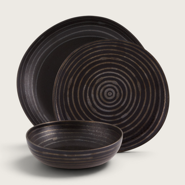 Kindred & Kin Exuberant stoneware dinnerware set featuring black plates and a bowl with hand-applied concentric lines.