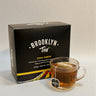 Kindred & Kin Brooklyn Tea ginger turmeric tea box with a glass mug of brewed tea and a biodegradable pyramid sachet.