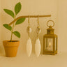 Kindred & Kin Serenity Cowrie Earrings: white cowrie shells wrapped in brass with carved bone leaf pendants.