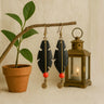 Kindred & Kin Sutura Feather Drop Earrings: black bone feathers, brass wire, coral beads, and brass spiral detail.