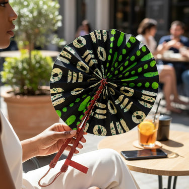 Kindred & Kin black folding fan with abstract lime green and cream pattern. Leather-wrapped handles.