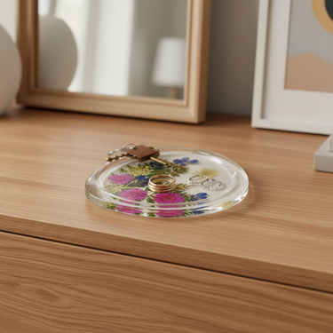 Kindred & Kin Belart botanical resin catch-all dish featuring pressed flowers like daisies and forget-me-nots on a wood table.