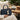 Kindred & Kin hand-crocheted natural raffia dog bone bag charm clipped to a navy blue leather handbag